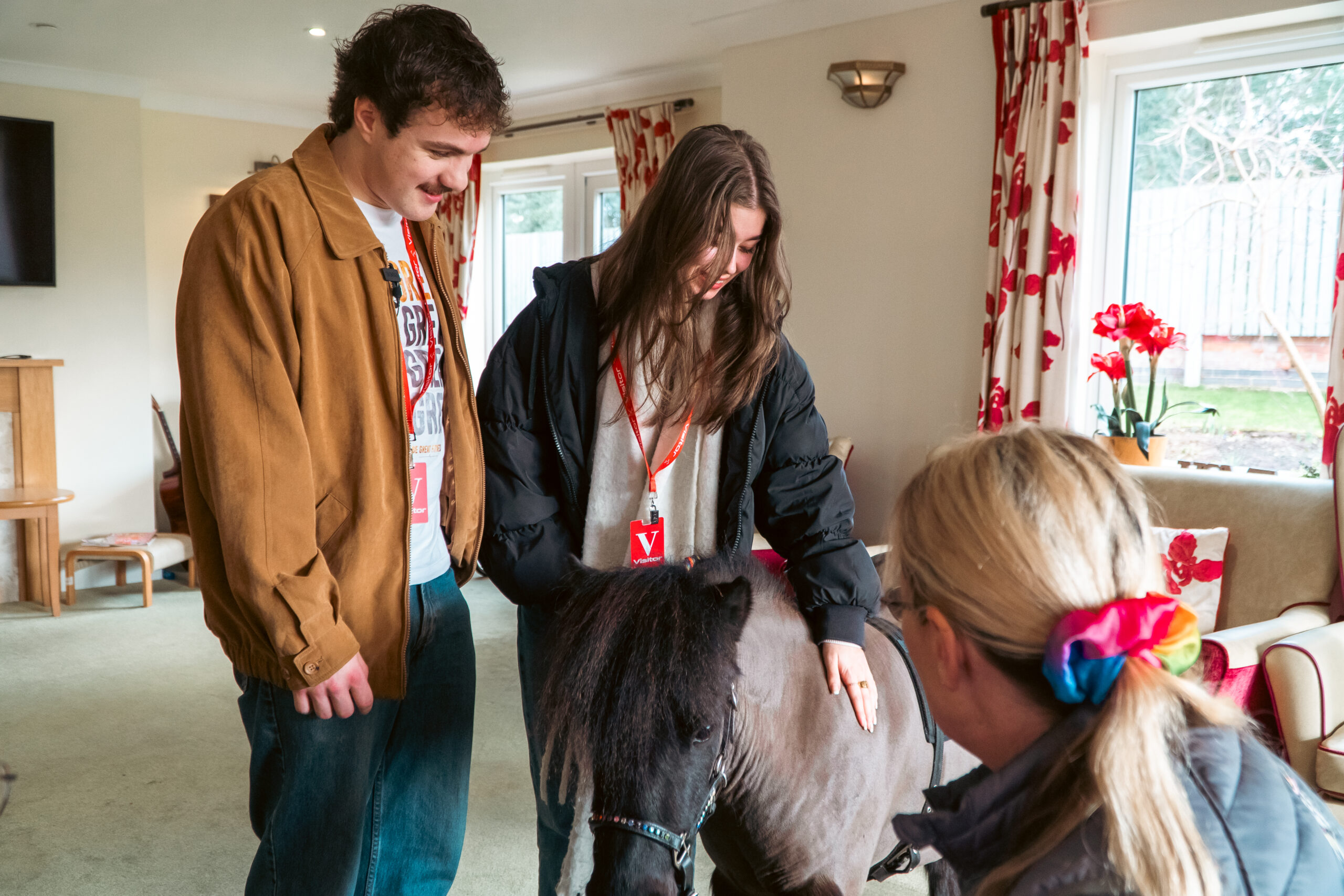 Visitors and staff at Cloverleaf Care Home engaging with a Shetland pony during its therapeutic visit.