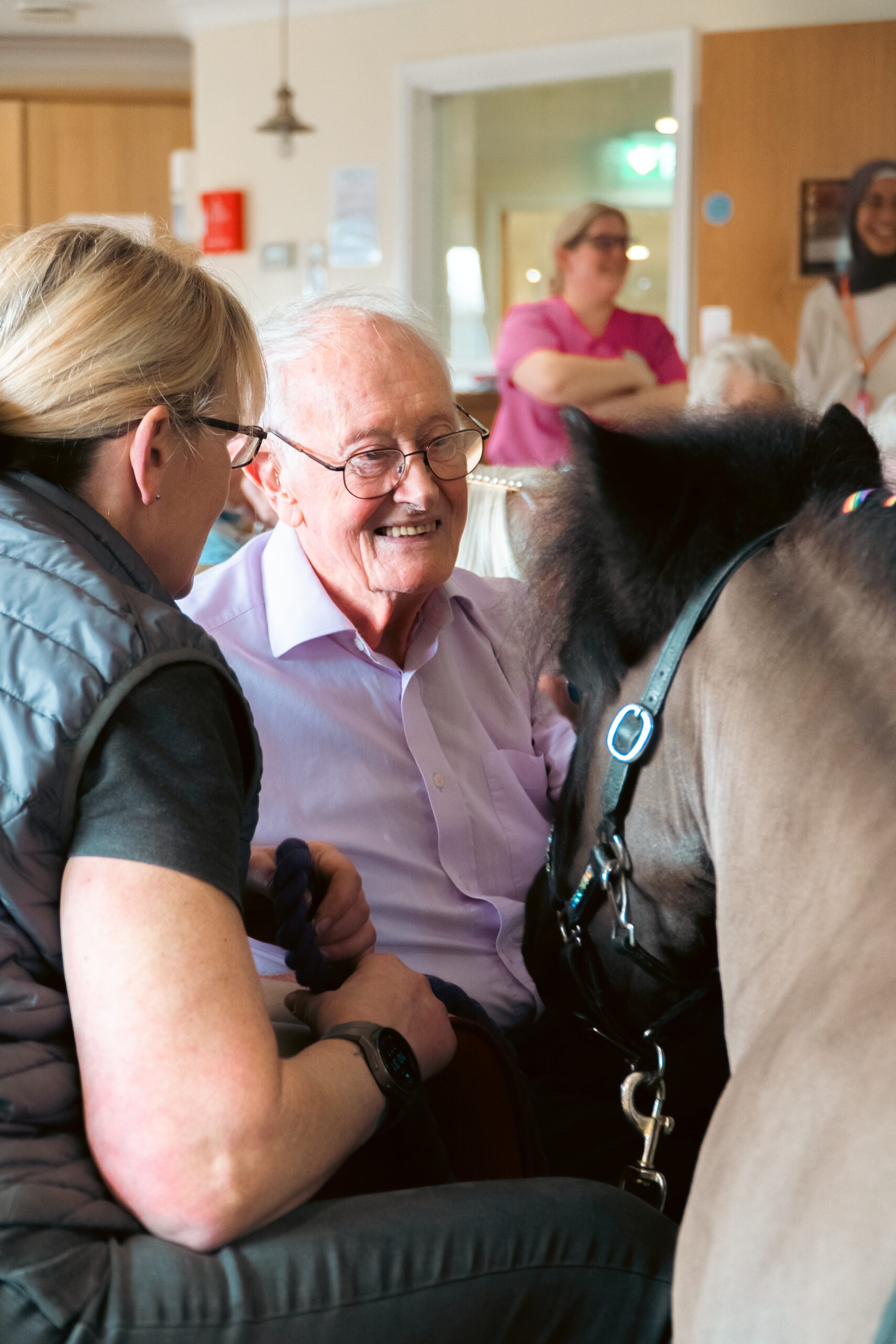 A resident of Cloverleaf Care Home enjoying a close moment with a Shetland pony during its visit.